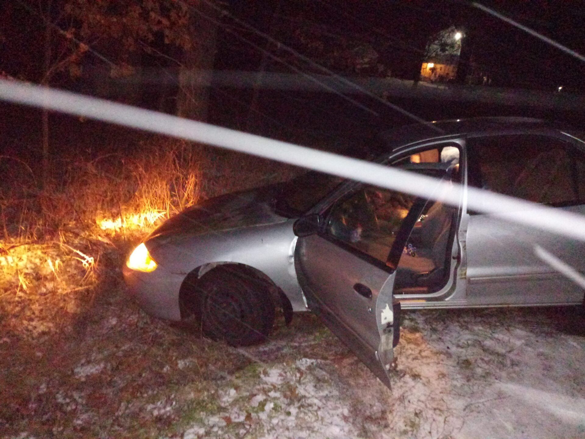 A silver car is parked in the snow with its door open