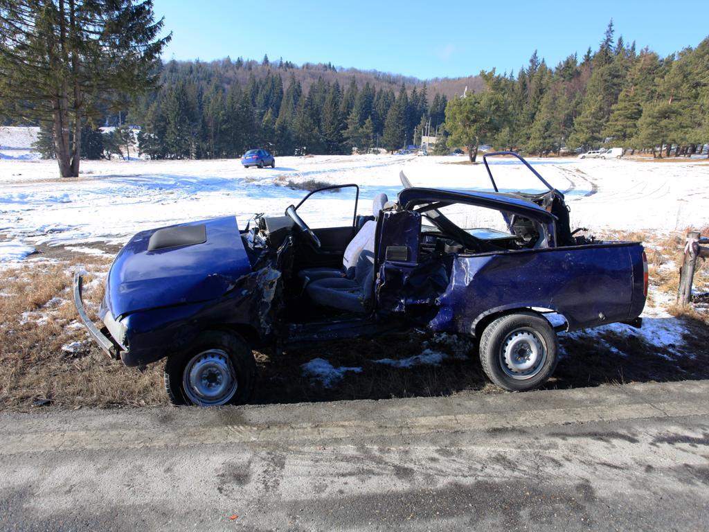 A wrecked blue truck is parked on the side of the road