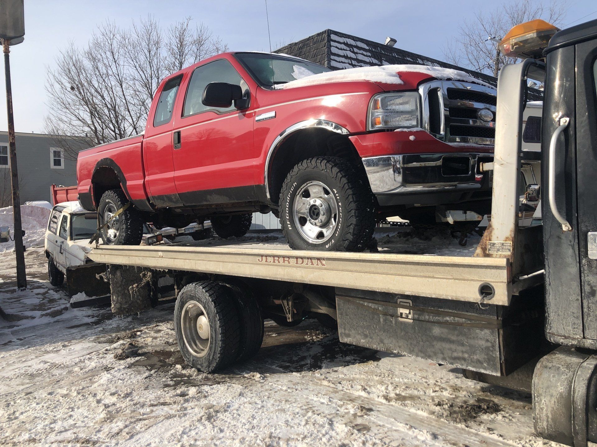 A red truck is on the back of a tow truck