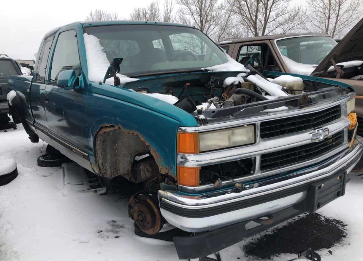 A blue truck with the hood up is sitting in the snow