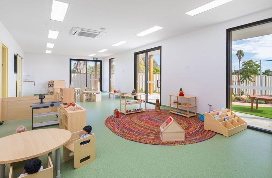 Interior play space | Brightly lit with natural light | Soothing green floor | Vibrant red rug | Wooden play furniture
