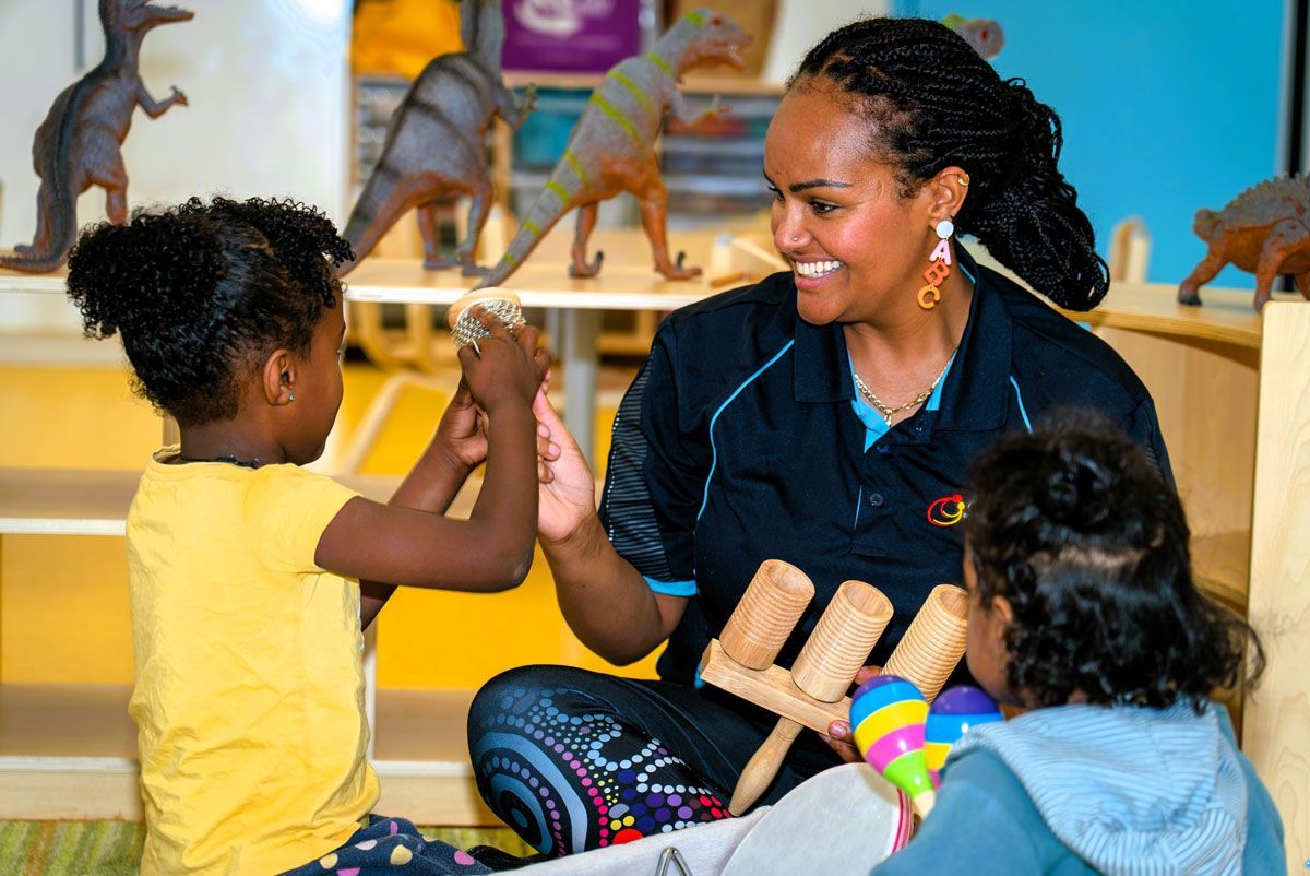 Carer with Two Kindy Children | Carer and one child both holding hairbrush together
