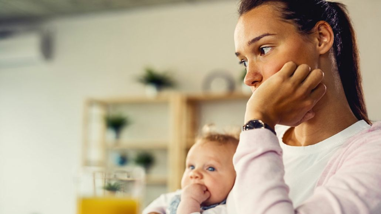 A thoughtful mother holding her baby, illustrating an adoption decision after giving birth.