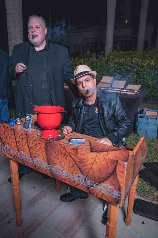 man sitting at a table, smoking a cigar