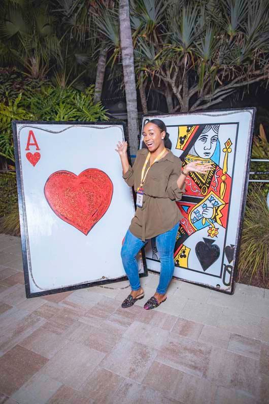 A woman is standing next to two giant playing cards.