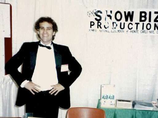 A man in a tuxedo stands in front of a sign that says show biz production