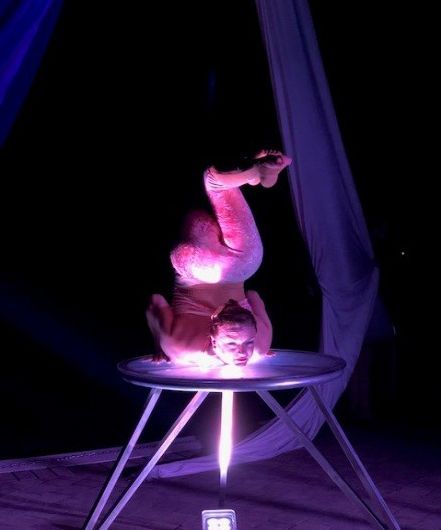 A woman is doing a handstand on a table in the dark.