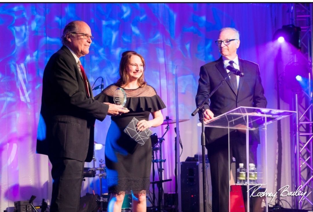 A man in a suit is giving an award to a woman in a black dress.