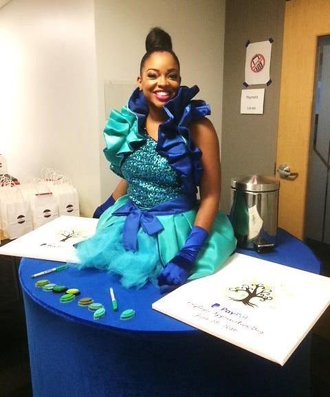 A woman in a blue and green dress sits at a table