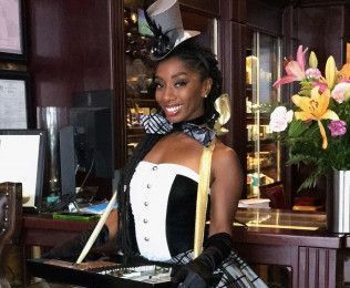 A woman wearing a top hat and gloves is holding a tray