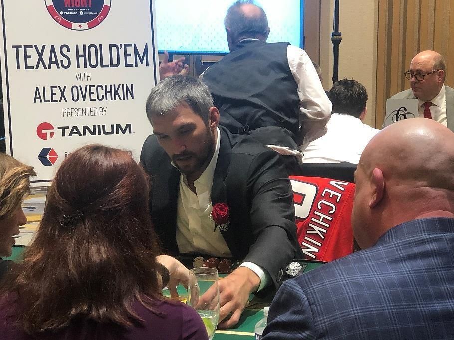 A man in a suit is playing poker with a sign that says texas hold 'em