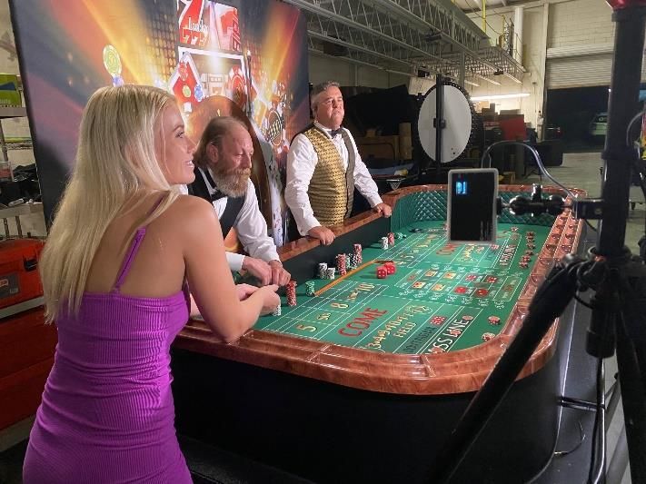 A woman in a purple dress is standing in front of a roulette table.