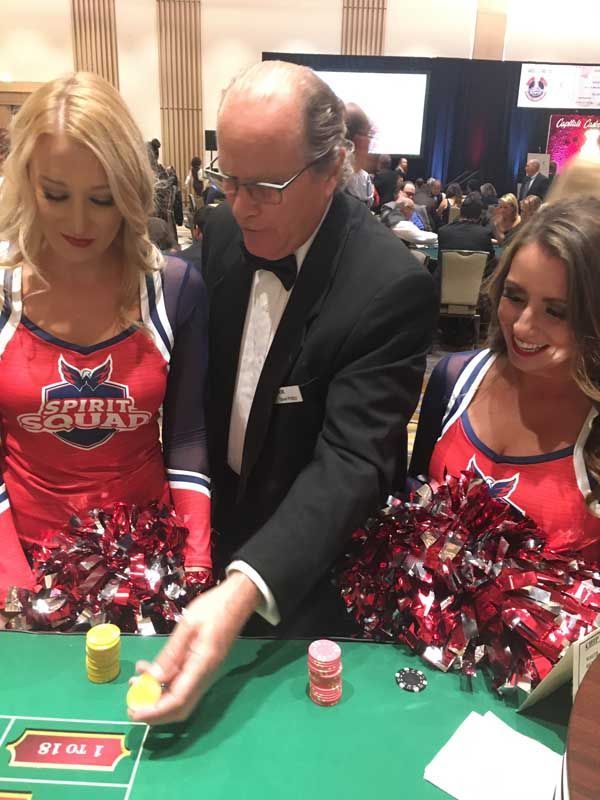 A man and two cheerleaders are playing a game of poker