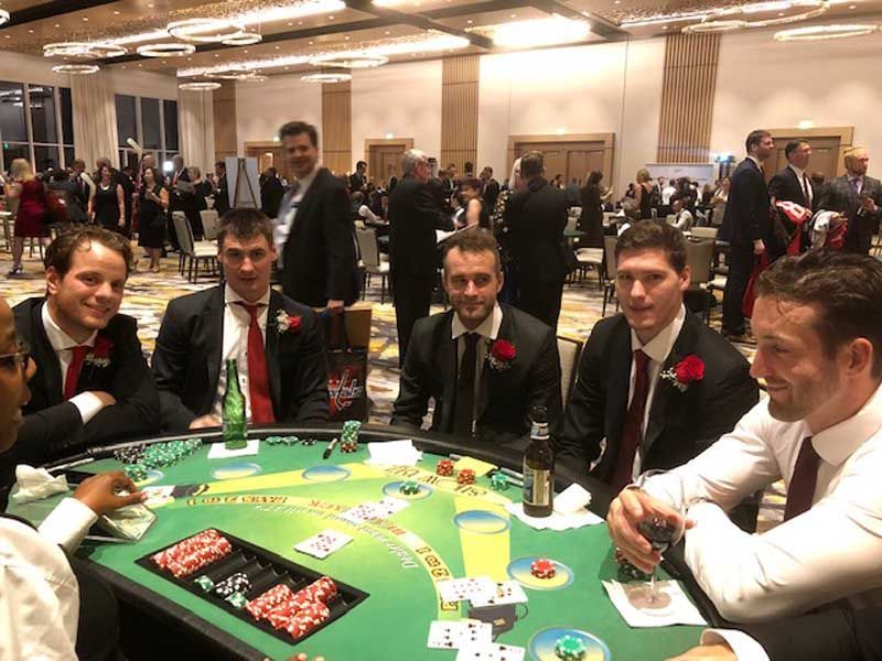 A group of men are sitting around a poker table.