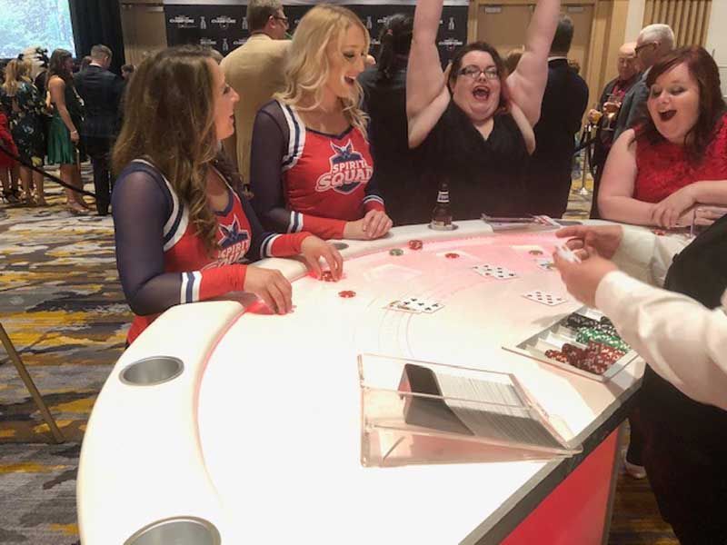 A group of cheerleaders are playing a game at a table.
