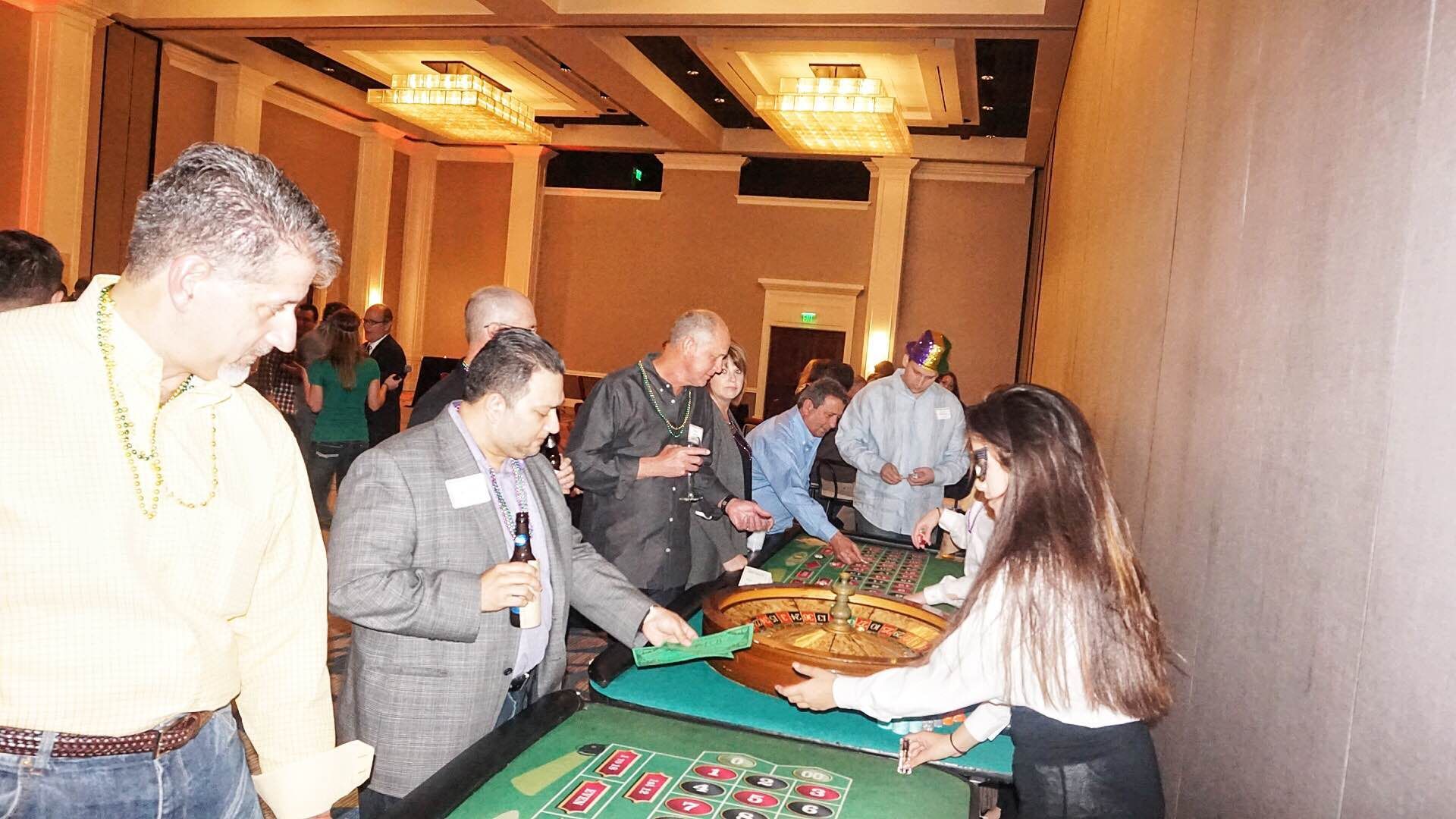 A group of people are playing roulette at a table in a room.