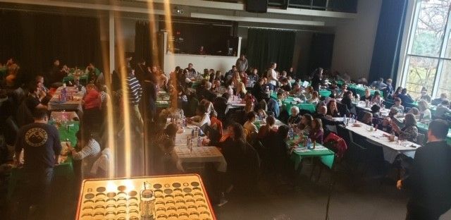 A large group of people are sitting at tables in a large room.