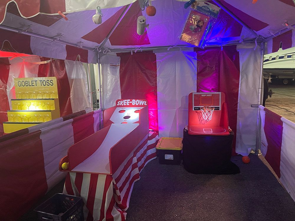 The inside of a carnival tent with a basketball hoop and a table.