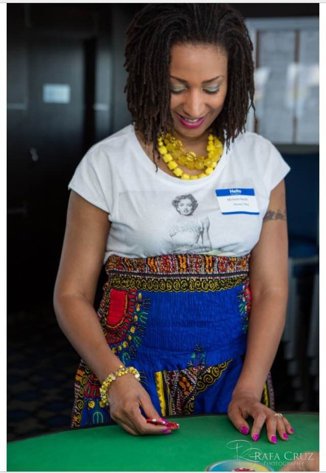A woman in a white shirt and blue skirt is standing at a table.