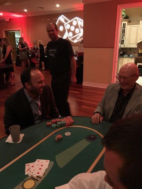 A group of men are sitting around a poker table