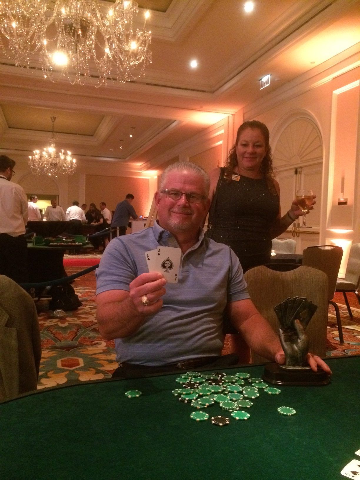 A man is sitting at a poker table holding an ace of spades card