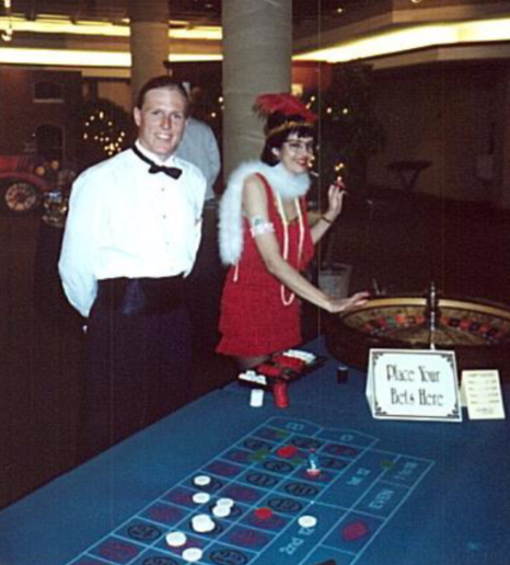 A man in a tuxedo stands next to a woman playing roulette