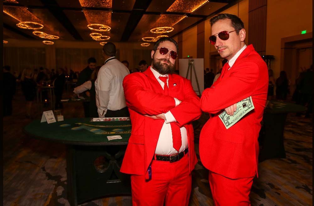 Two men in red suits and sunglasses are standing next to each other in a room.