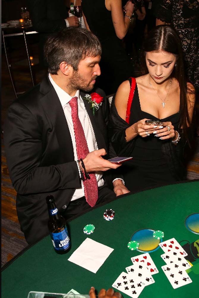 A man in a suit and tie is playing poker with a woman in a black dress
