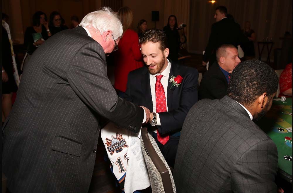 A man in a suit and tie is being helped by another man
