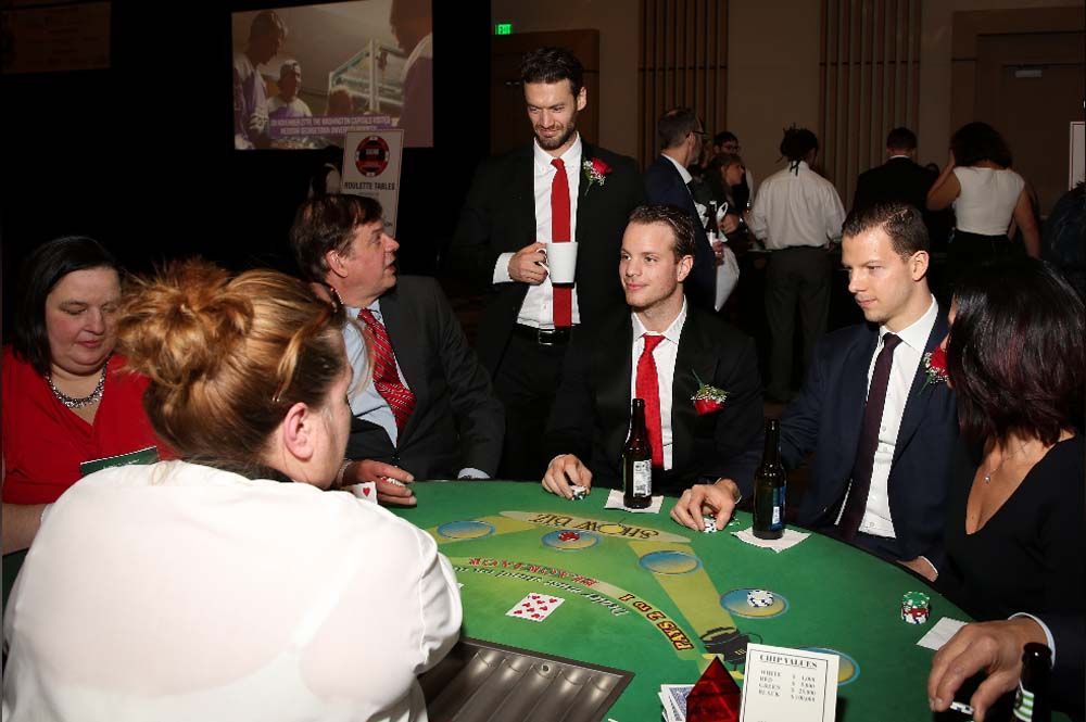 A group of people are sitting around a table playing poker.