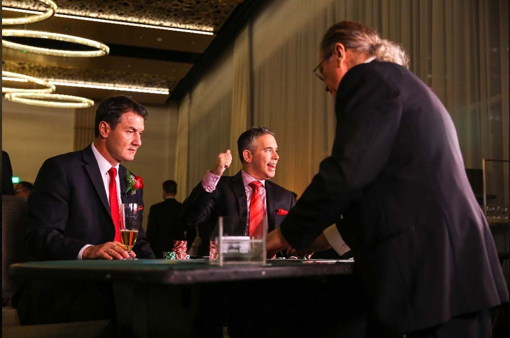 Three men in suits and ties are sitting at a table playing poker.