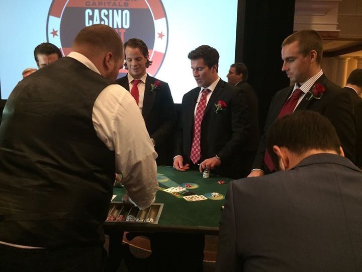 A group of men playing poker in front of a screen that says casino