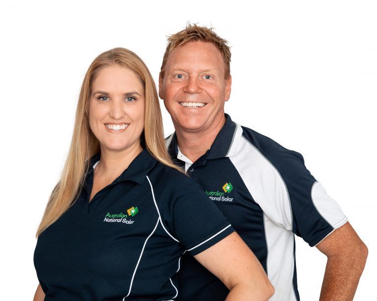 Two team members in navy and white branded polo shirts posing against a white background