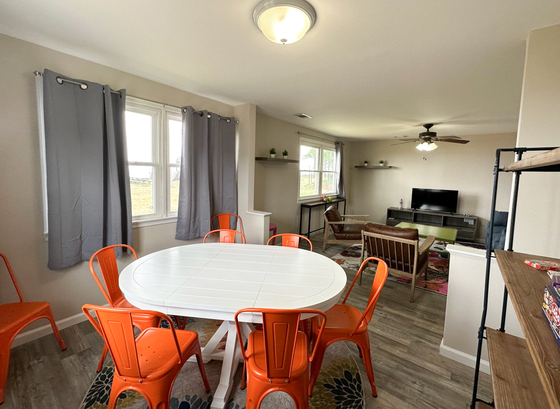 Dining area with round white table and orange chairs, leading into a living room.