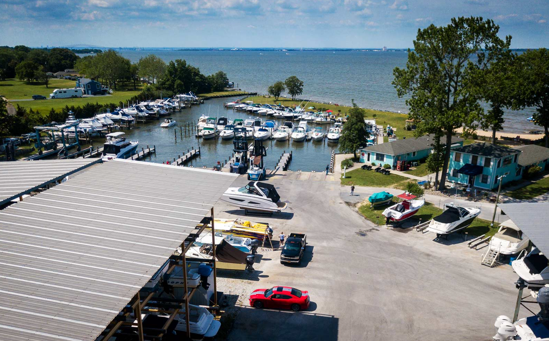 Marina with boats docked, boat launch area, and blue water under a partly cloudy sky.
