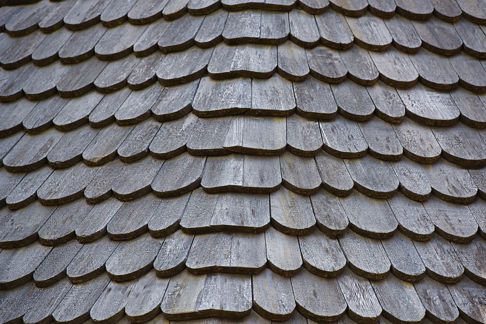 Close-up of gray overlapping roof shingles with a textured, curved pattern