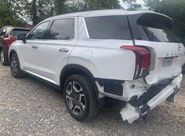 White Hyundai Palisade SUV with rear-end damage, parked outdoors.