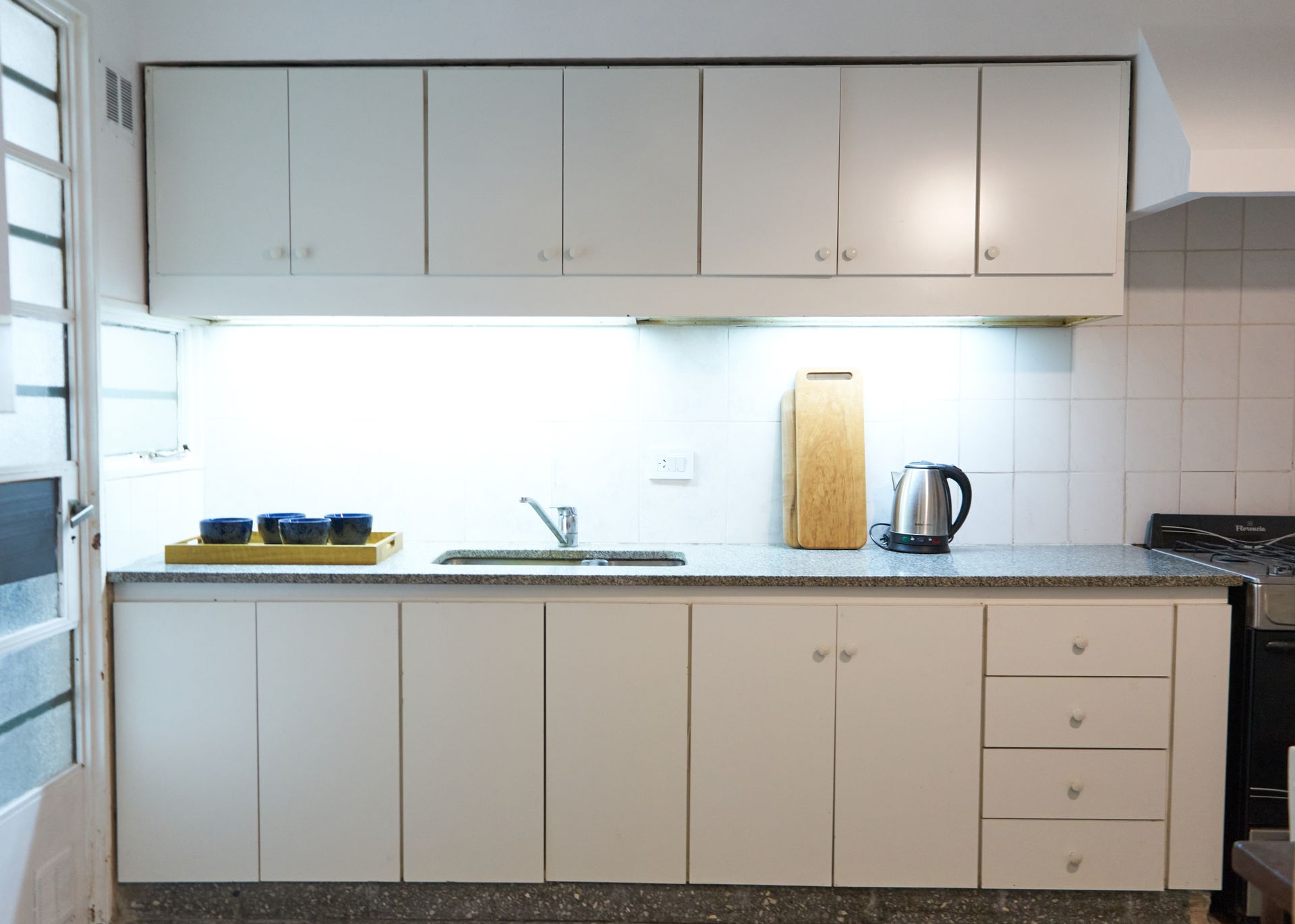Cocina blanca con gabinetes, encimera, fregadero y electrodomésticos.