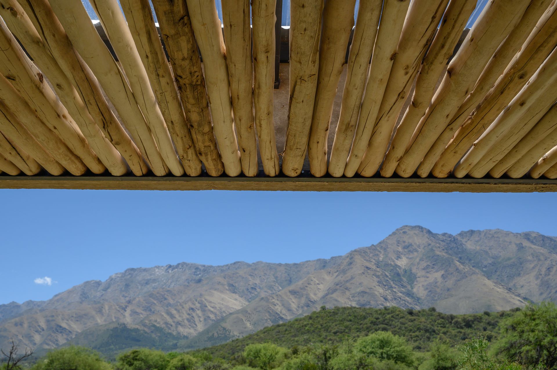 Los listones de madera del techo enmarcan una vista de la montaña en un día soleado.