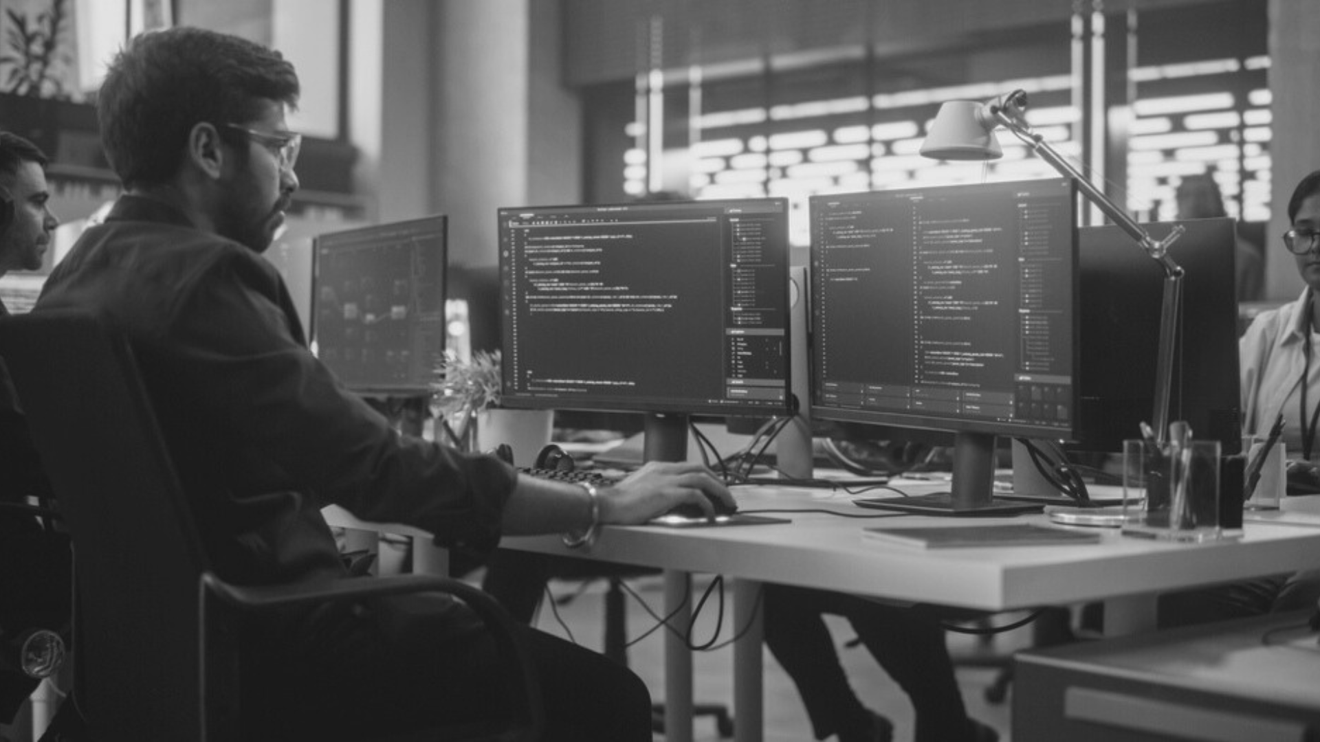Offshore outsourcing man is sitting at a desk in front of a computer.