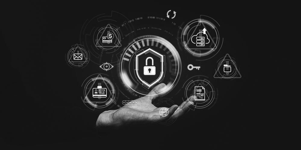 Hand holding a digital shield with a lock, surrounded by alert symbols, against a dark background, suggesting cybersecurity.