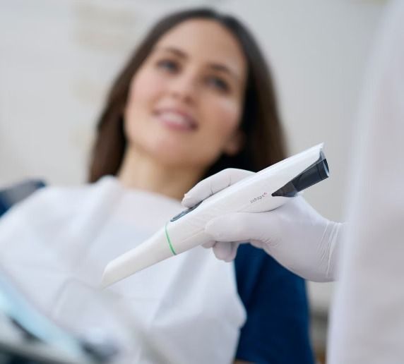 A gloved professional points to a specific area on a panoramic dental X-ray displayed on a screen.