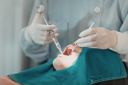 A gloved professional points to a specific area on a panoramic dental X-ray displayed on a screen.