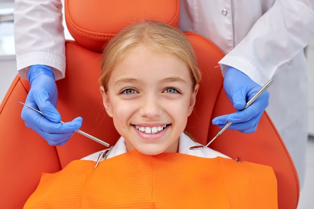 A gloved professional points to a specific area on a panoramic dental X-ray displayed on a screen.