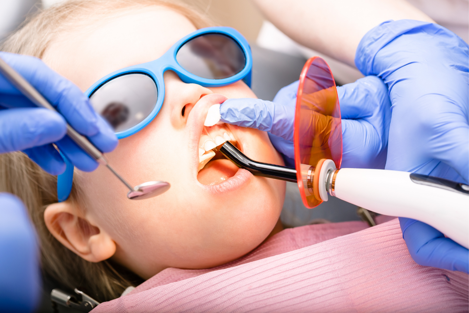 A gloved professional points to a specific area on a panoramic dental X-ray displayed on a screen.