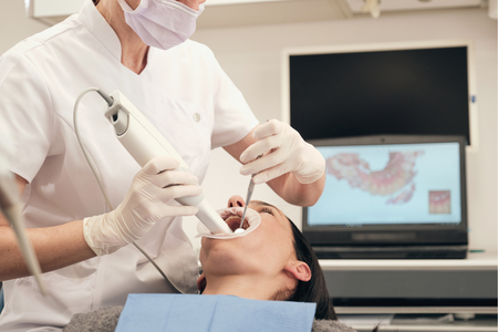 A gloved professional points to a specific area on a panoramic dental X-ray displayed on a screen.
