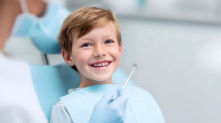 A gloved professional points to a specific area on a panoramic dental X-ray displayed on a screen.