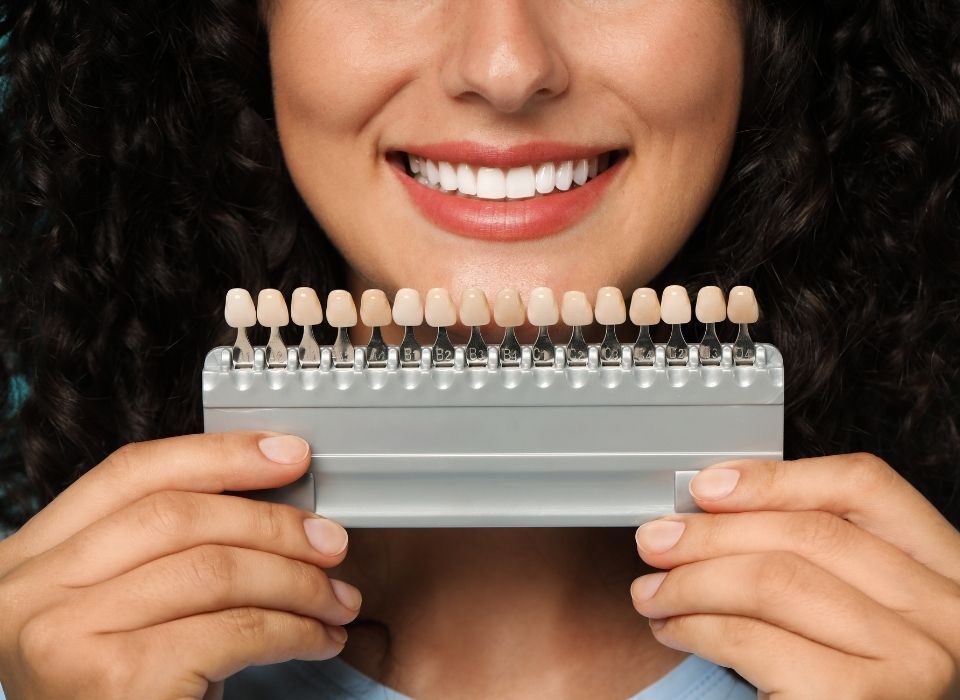 A gloved professional points to a specific area on a panoramic dental X-ray displayed on a screen.