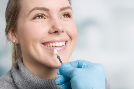 A gloved professional points to a specific area on a panoramic dental X-ray displayed on a screen.