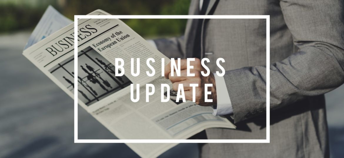 A person in a gray business suit holds a newspaper titled 